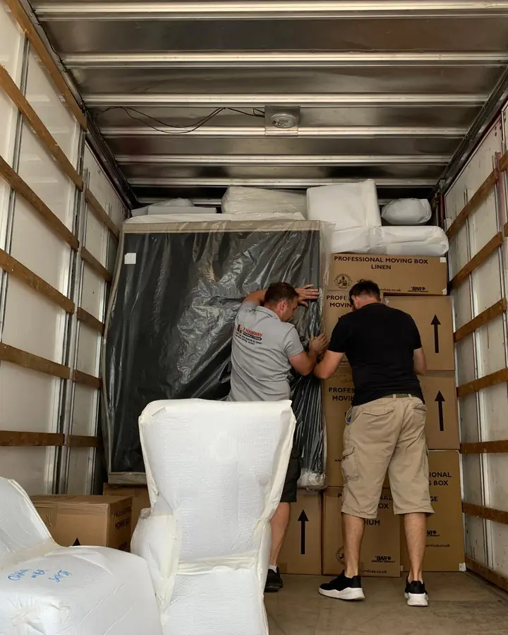 Two of the Hanway crew loading wrapped furniture into a removal truck