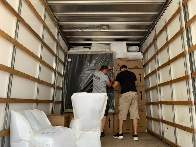 Two of the Hanway crew loading wrapped furniture into a removal truck