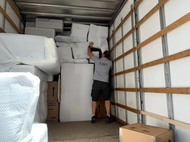 Sofas and mattresses wrapped and stacked floor to ceiling inside a Hanway van